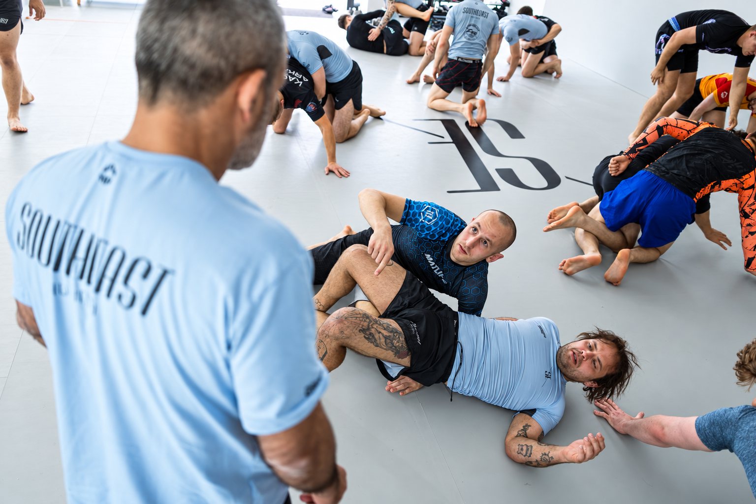 Uczestnicy zajęć Jiu-Jitsu ćwiczą techniki w parach na macie Southeast